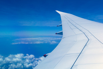 Obraz premium View from window seat of an airplane overlooking blue sky and clouds.