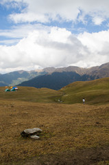 Fototapeta premium Solo trekker walking towards a distant campsite on the himalayan mountains on a sunny day