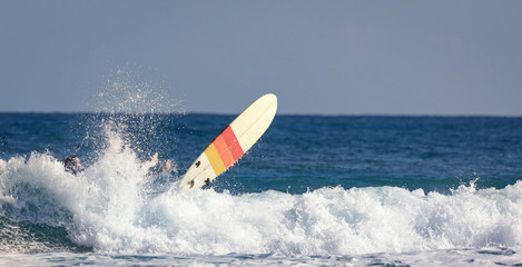 Surfer legs in water and surfing board in the air after falling a wave. Water sport activity, surfboard in the air