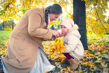 Portrait of a happy mother giving bottle feeding to her baby outdoors. young beautiful girl with a...