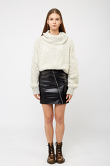 A girl dressed in a white sweater and a black eco-leather skirt