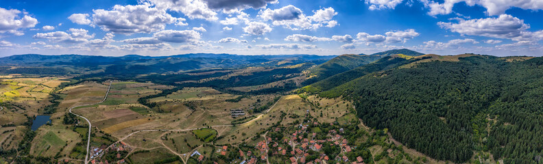 Fototapeta na wymiar Amazing Aerial panorama from a drone of countryside fields, trees, a mountain peaks at cloudy day. Countryside. Stunning detail