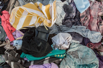 old clothes background, looking down on piles of colourful old clothes discarded on the ground, an...