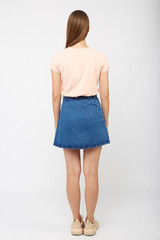 Teenager girl in a denim blue skirt on a white background.