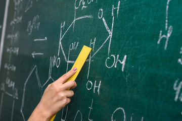 Female hand pointing at chemical formula on blackboard close up