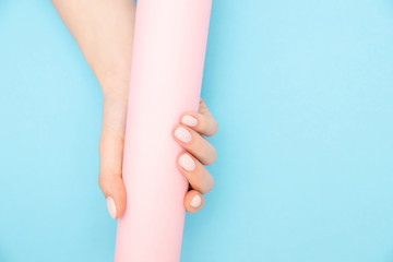 Beautiful female hands with stylish nail manicure gel polish on pink and blue background, top view. Skin care concept
