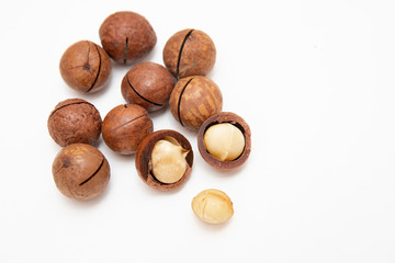 Pile macadamia nuts open kernels and shells on white background, top view