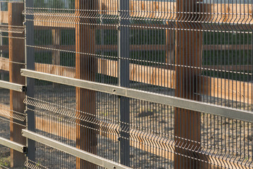 Fence or fence made of metal grate with large cells on a wooden support