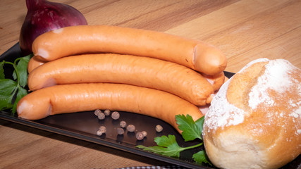 Bockwurst mit Brötchen auf schwarzem Teller