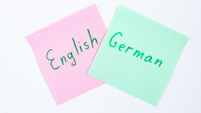 Stop motion animation top view flat lay of two languages english and german which written on the reminder notepaper of different colors