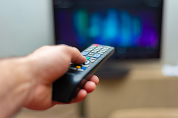 A man watches tv and holds the shift control with his left hand.