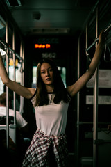 Woman with long hair in bus. Black and white portrait. Riding on train. Looking somewhere. Street style fashion outfit. Urban lifestyle outfit. White t-shirt. Rebel girl. Different emotions.