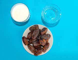 Ramadan iftar food, delicious date fruits, water and laban on blue background 