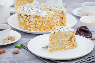 Traditional Hungarian Esterhazy cake on a white plate on a stone background with a cup of coffee,...