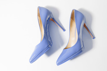 Closeup blue women patent leather shoes isolated on white background. Stilettos shoe type. Summer fashion and shopping concept. Luxury and glamour party ladies wardrobe accessory. Selective focus