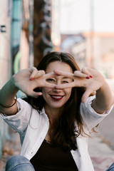 Pretty girl in white shirt, blue jeans with red lips. Posing in street. Sitting on the floor. Long hair. Bubble gum. Sunny day. Art district. Skinny girl modeling. Pretty woman, fashion girl.