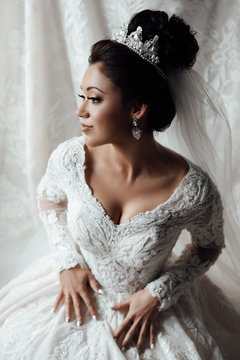 Gorgeous bride portrait with make-up in the morning in room. Pretty brunette bride with hair style and diadem on her head. Beautiful charming. Beautiful woman getting ready for wedding day. 