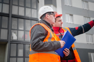 Fototapeta na wymiar An engineer with a hard hat and helmet discussing a project at a construction site with a team leader in autumn or winter. architecture construction concept. Industrial safety