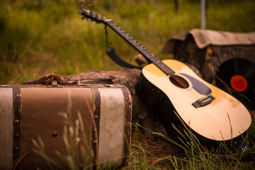 Traveling musician kit, guitar, suitcase an backpack, on the grass, camp of musician boys.