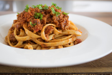 Food photography of traditional Italian pasta dish fettucine bolognese or ragu in white bowl