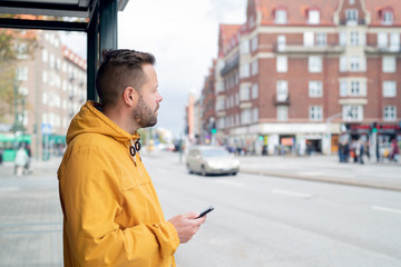 Man at bus stop with cell phone