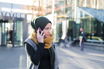 Woman wearing headscarf talking on phone in city