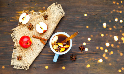 Christmas background. Hot mulled wine with ingredients in cup on wooden background. The concept of celebration and cooking warming drinks.Top view, copy space
