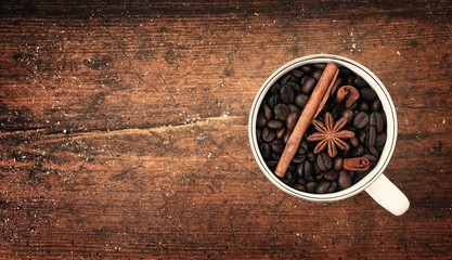 Fototapeta na wymiar Coffee beans and spices in cup on wooden table