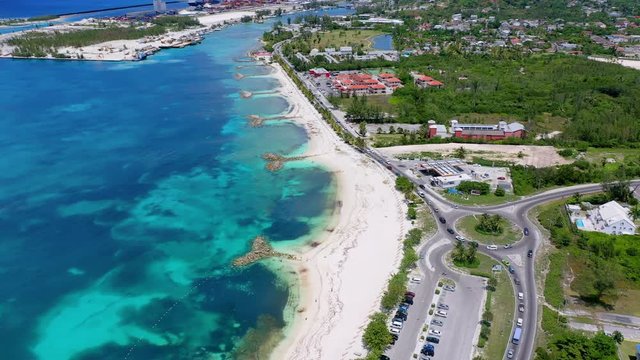 Aerial: Cars Driving Along Waterfront Road Near Beach and Neighborhood - Nassau, Bahamas
