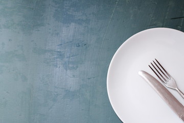 White plate with fork and knife on table