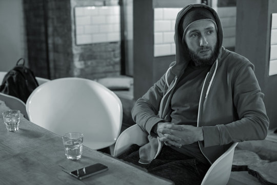 Black and white image, a man sits in a bar and drinks alcohol. Depression and alcoholism.