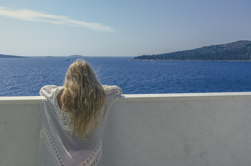 mysterious princess with long blond hair looking from the balcony back view