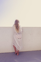 adorable girl with long blond hair looking from the balcony to the blue croatian sea