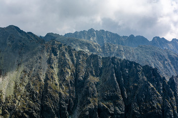 Cloudy day in the mountains. Rocky mountain ridges over which dark clouds swirl.