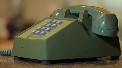 Retro push button rotary dial telephone ringing. Incoming phone call on vintage avocado green landline phone.