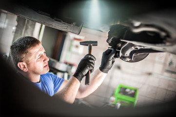 Auto mechanic repairer checking condition under car on vehicle lift