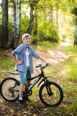 Fototapeta na wymiar Boy in countryside riding bike in summer park smiling at camera