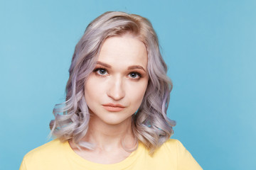 Fototapeta premium Closeup portrait of blond female in the yellow clothes isolated over the blue background