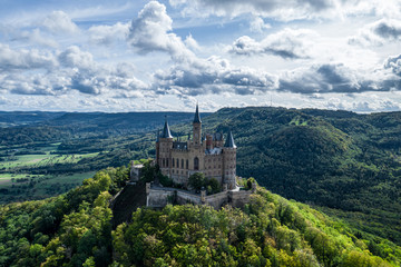 Aerial panorama of Burg Hohenzollern (Hohenzollern castle) with hills and villages surrounded by forests with beautiful foliage