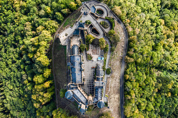 Aerial panorama of Burg Hohenzollern (Hohenzollern castle) with hills and villages surrounded by forests with beautiful foliage
