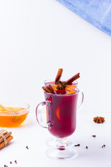 Glass of hot mulled wine with spices and honey on white background. Christmas mulled wine with orange, star anise and cinnamon. Two glasses of winter Christmas drink