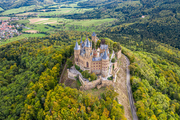 Fototapeta premium Aerial panorama of Burg Hohenzollern (Hohenzollern castle) with hills and villages surrounded by forests with beautiful foliage