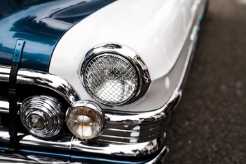 Close-up van koplampen van een witte en blauwe retro auto