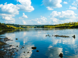 image of riverbank and clouds reflected in the water