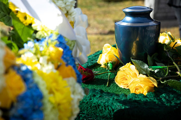Cremation urn at a funeral, with flowers in the foreground - obrazy, fototapety, plakaty