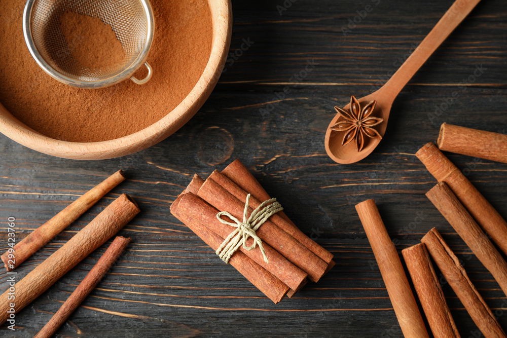 Poster Cinnamon sticks, powder and spoon on wooden background, top view