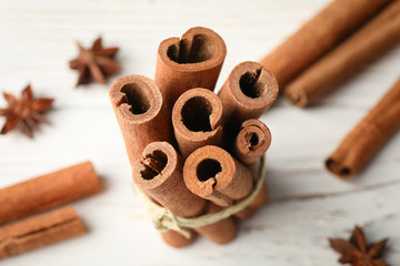 Cinnamon sticks on white wooden background, space for text and close up