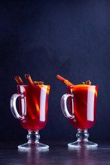 Glass of hot mulled wine with spices on dark background. Christmas mulled wine with orange, star anise and cinnamon. Two glasses of winter Christmas drink