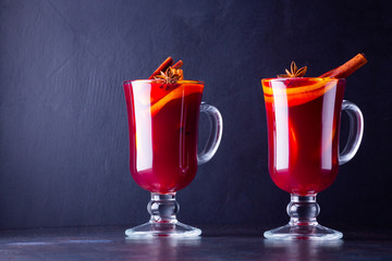 Glass of hot mulled wine with spices on dark background. Christmas mulled wine with orange, star anise and cinnamon. Two glasses of winter Christmas drink
