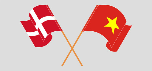 Crossed and waving flags of Vietnam and Denmark